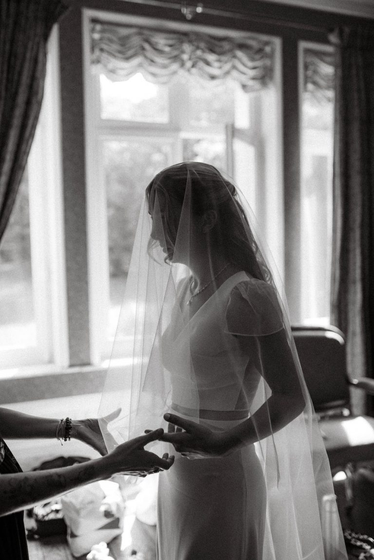 Alizée, la mariée, lors des préparatifs, ajustant son voile dans le château de Flixecourt, sa tenue deux-pièces visible.